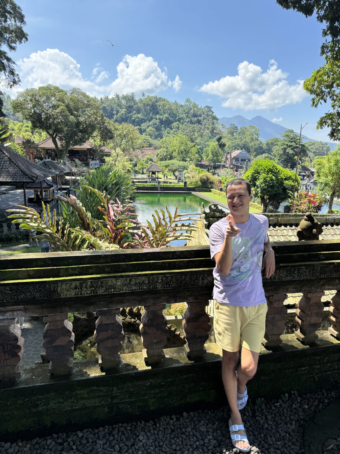 A traveler meditating at a Balinese temple, surrounded by lush nature